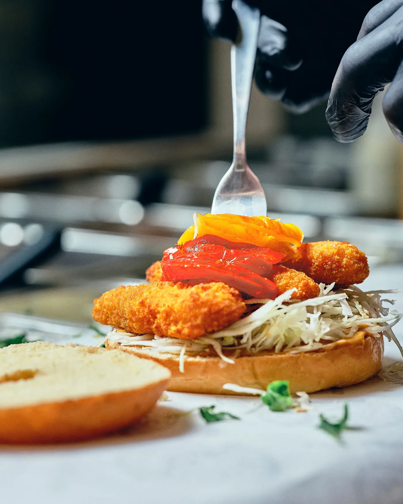 Poisson pané, poivrons et coleslaw posés sur un bagel ouvert