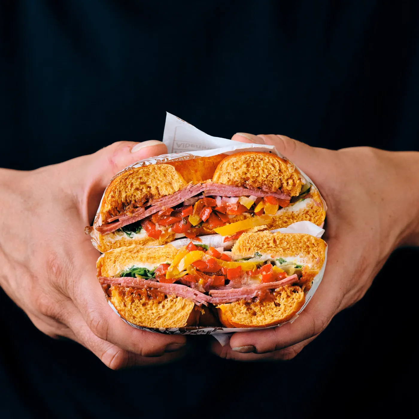 Un bagel coupé en deux, tenu à deux mains