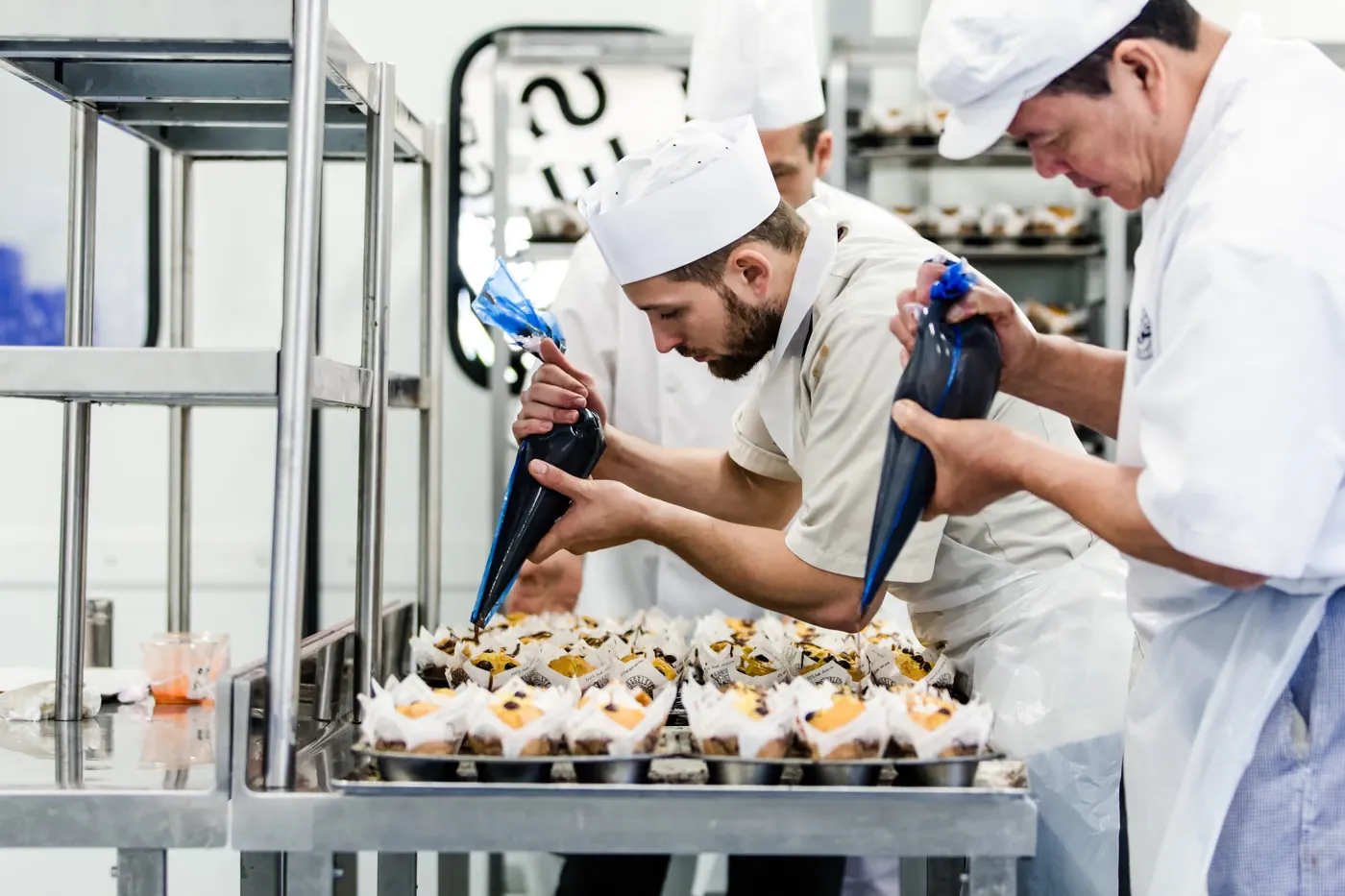 Des boulangers garnissent des bagels à la poche à douille dans la boulangerie centrale
