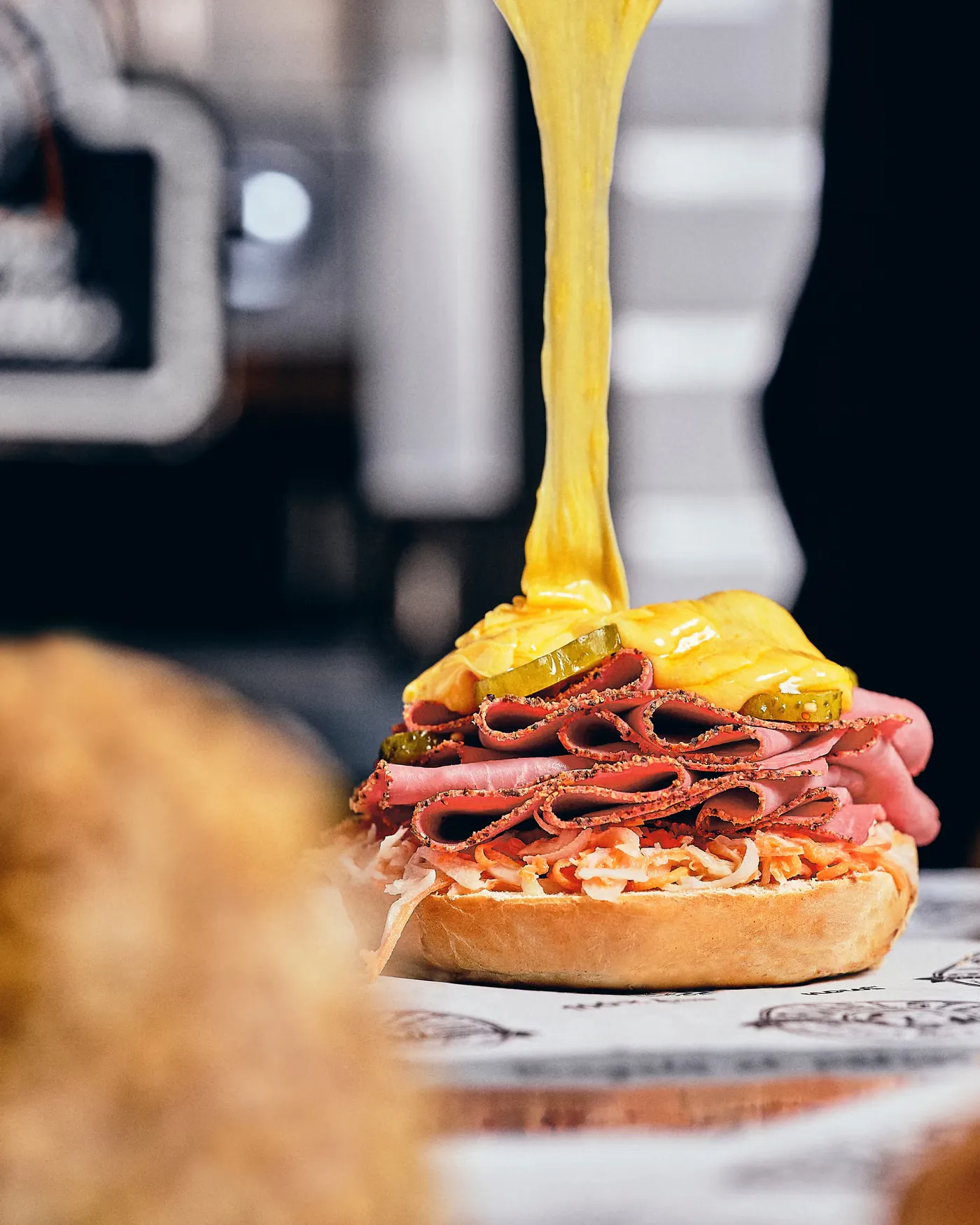 Cheddar fondu versé sur un bagel pastrami