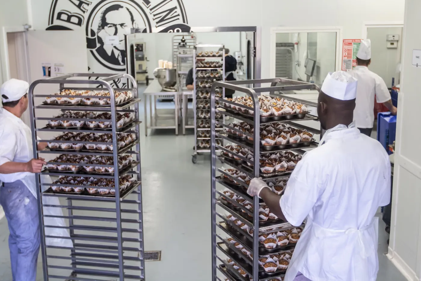 Deux boulangers déplacent des échelles chargées de muffins dans la boulangerie centrale