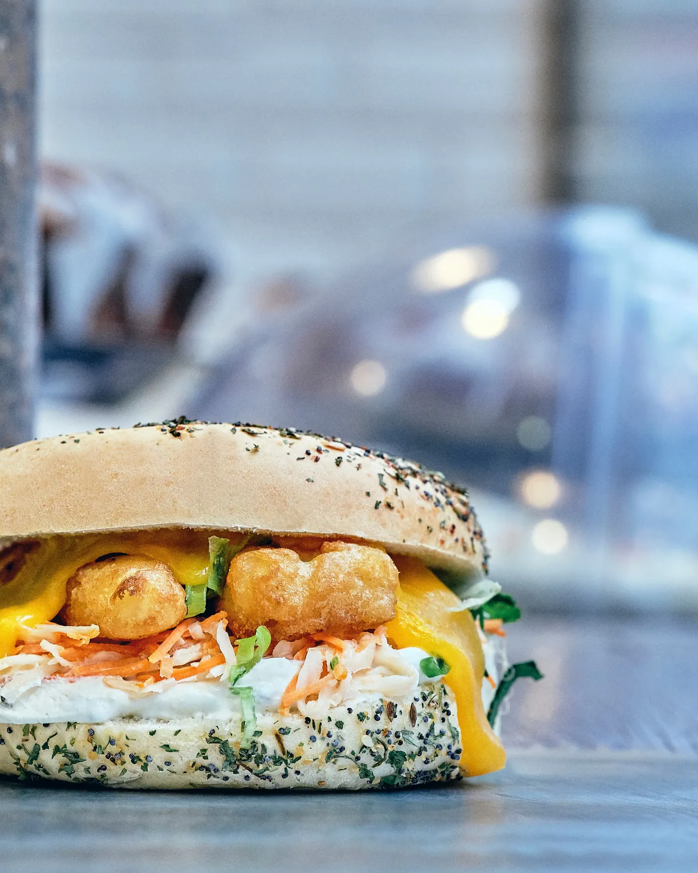 Gros plan sur un bagel everything garni de cheddar et de coleslaw