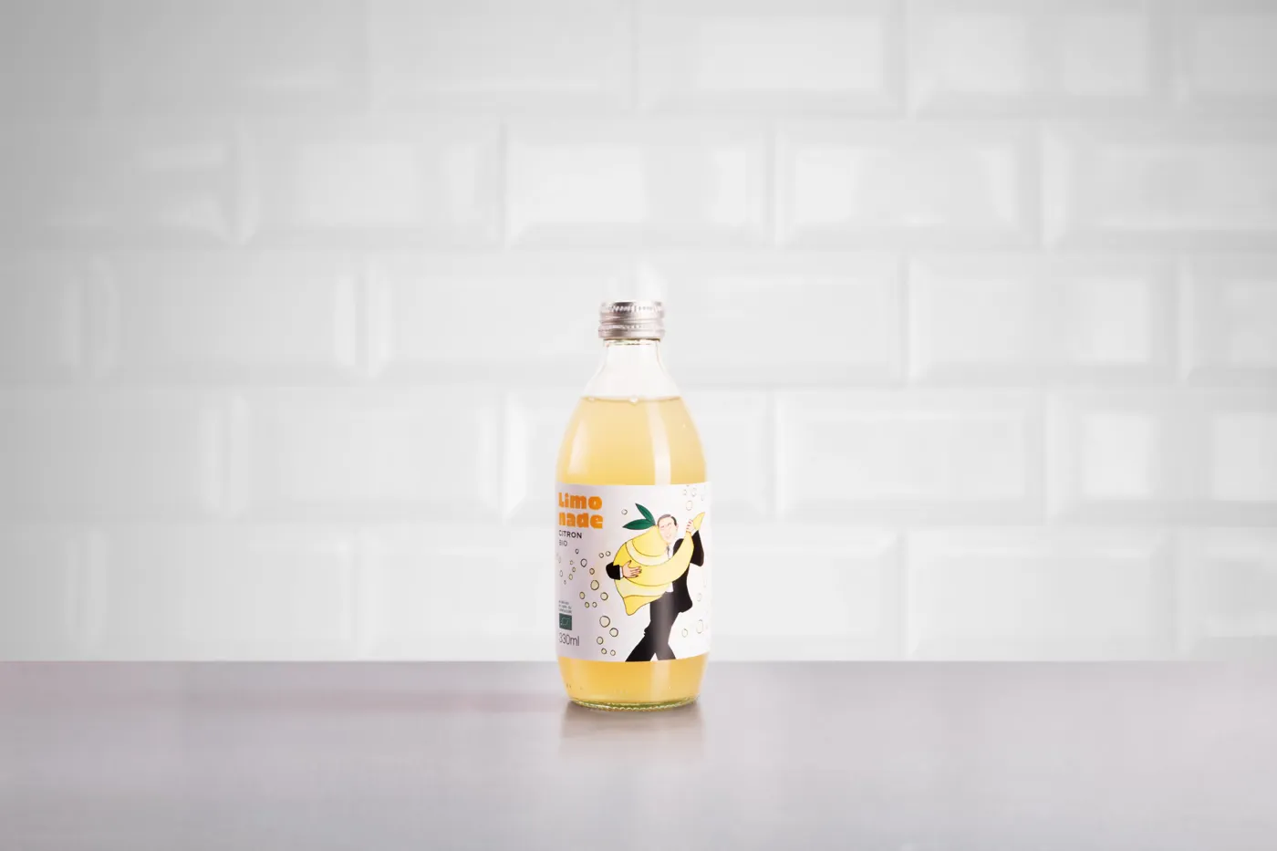 Bouteille de limonade citron devant un mur de carrelage blanc