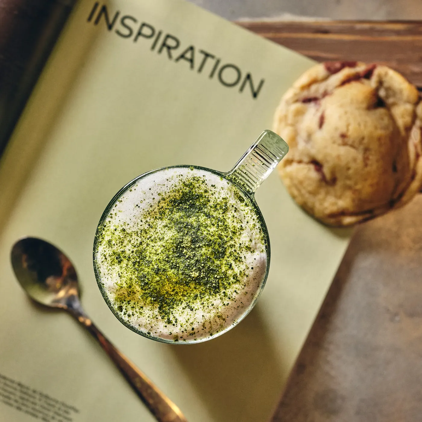 Matcha latte saupoudré de thé vert, posé près d’un cookie