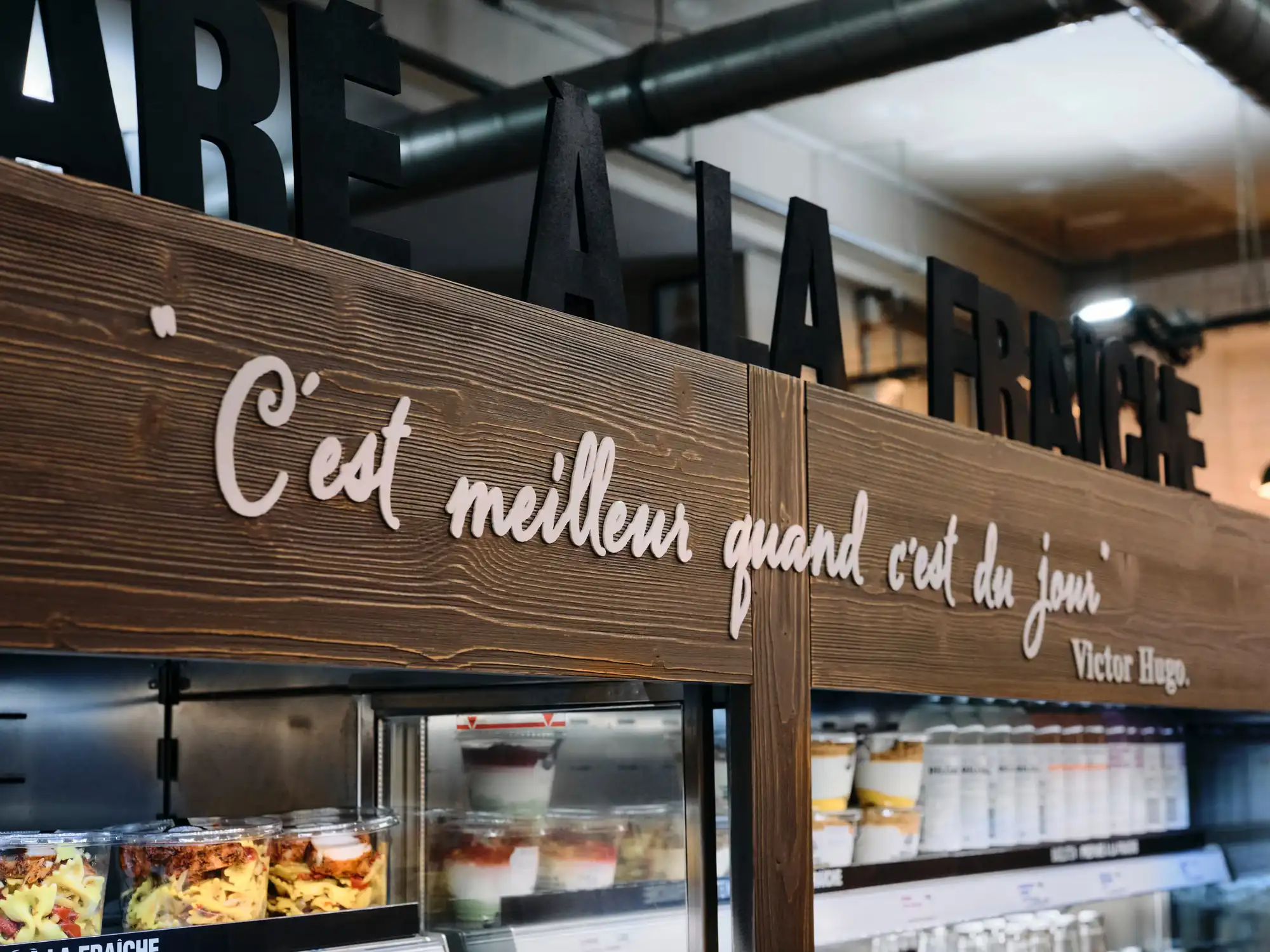 Panneau de bois manuscrit « C’est meilleur quand c’est du jour » au-dessus du comptoir d’un Bagelstein